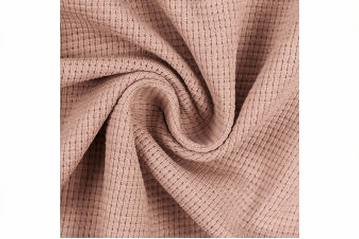 Thermal waffle knit fabric in dusty blush cotton with raised cellular texture, manufactured at Apex Corporation knitwear factory in Karachi Pakistan